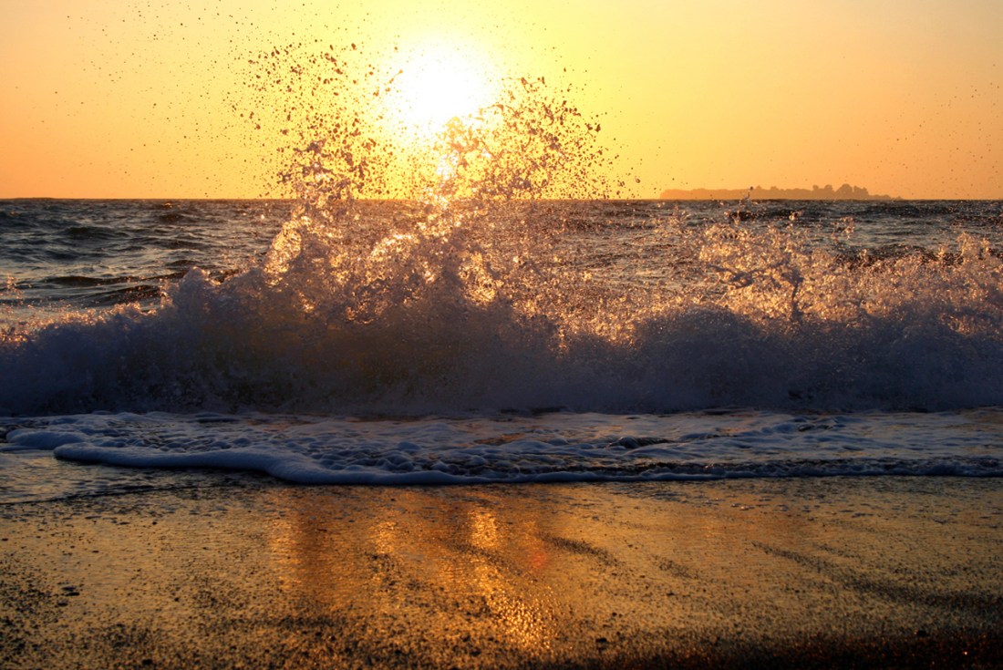 waves crashing on a beach at sunset